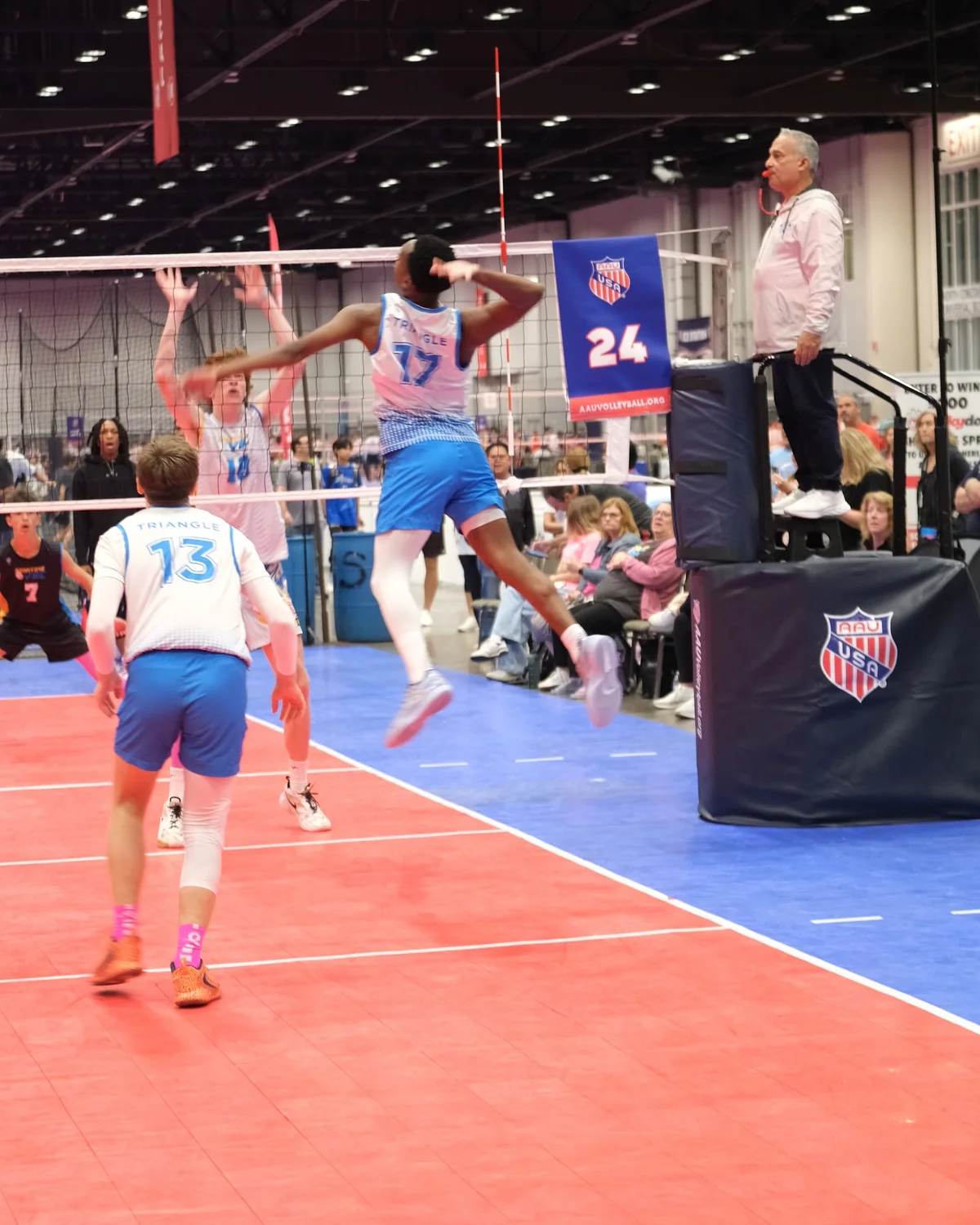 A boys' club volleyball player attacks at the net during a national tournament